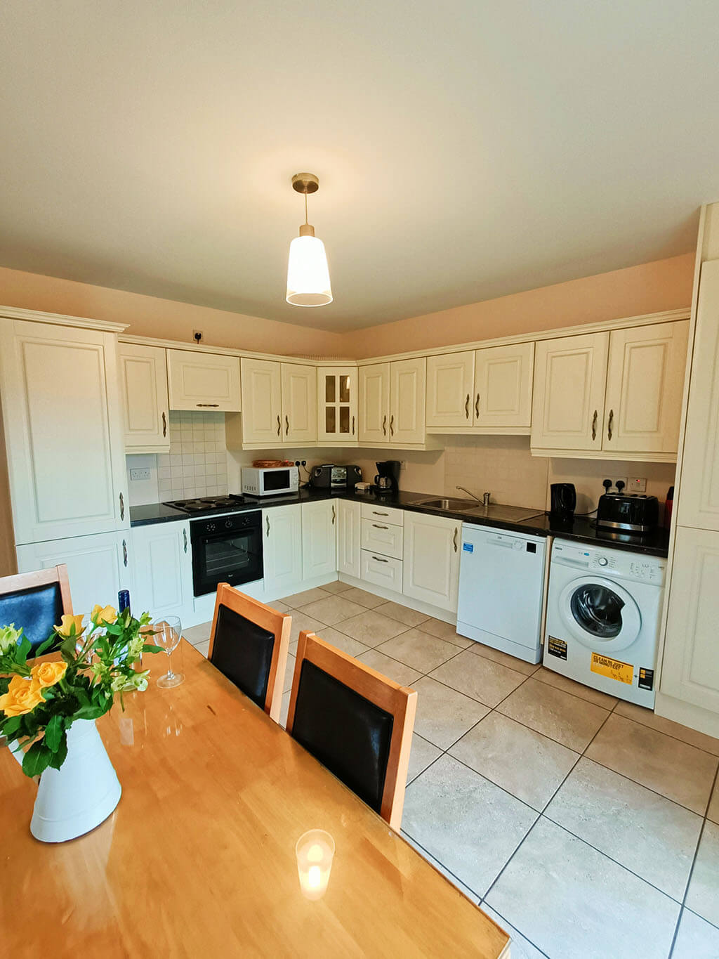 kitchen-flowers-wine-glasses-light-chairs-table-washing-machine-oven-dishwasher-cupboards-storage-donegal-ireland-cottage